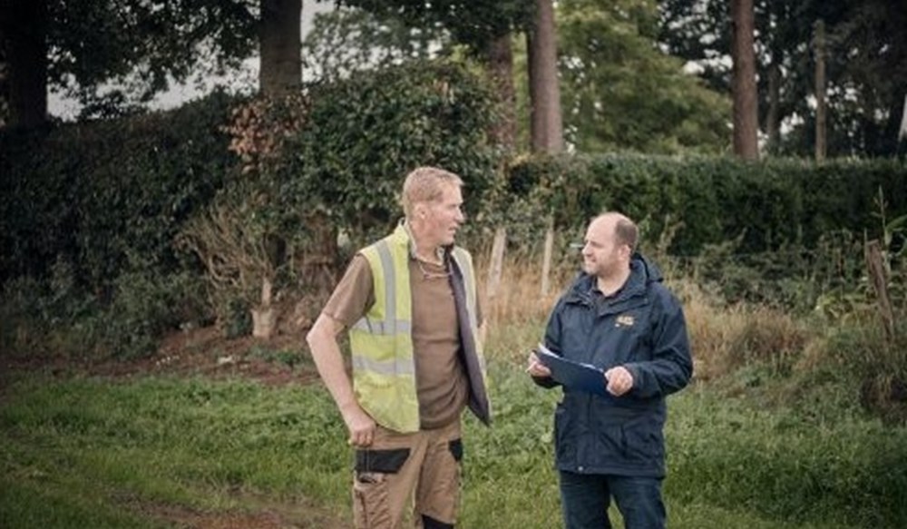 Two men talking in a field.